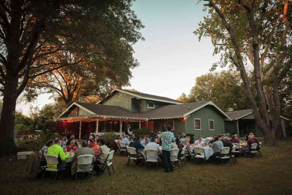 A photo of a backyard outdoor gathering with tables and chairs set up for guests to visit together