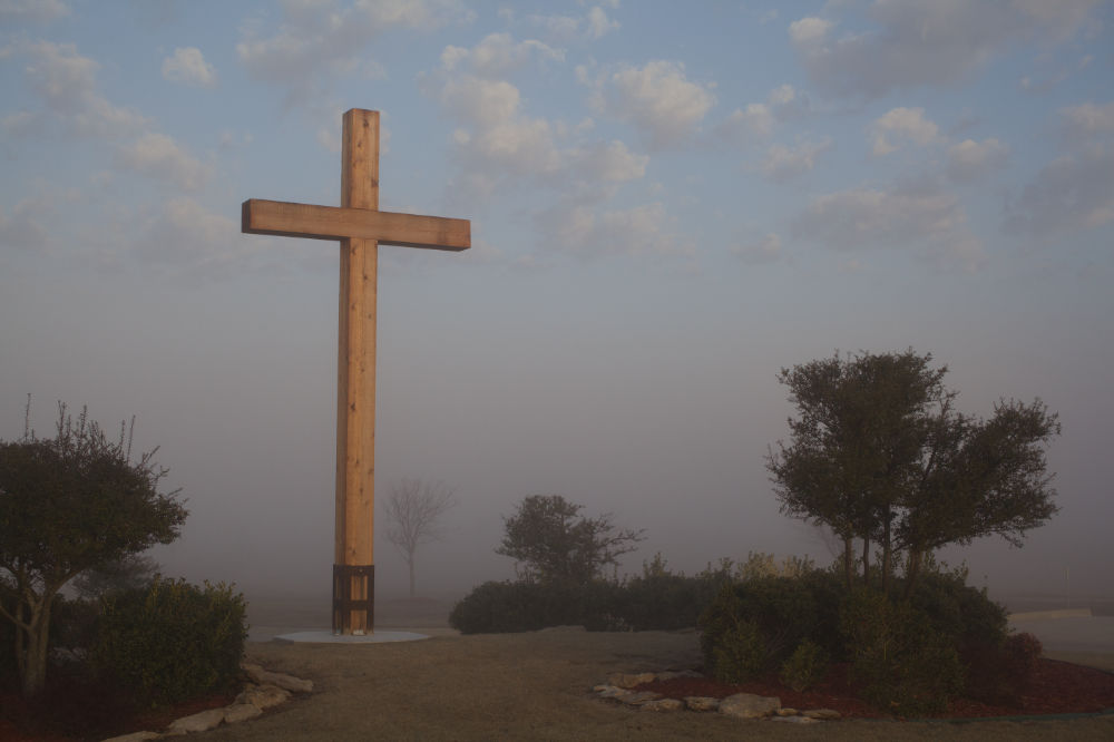 A statue of a crucifixion cross is lit by the early morning sun in Bartlesville, Oklahoma