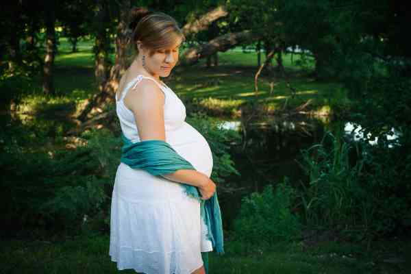 A photo of my Lisa, posing in front of a pond in Bartlesville, Oklahoma, while wearing a white dress and teal scarf