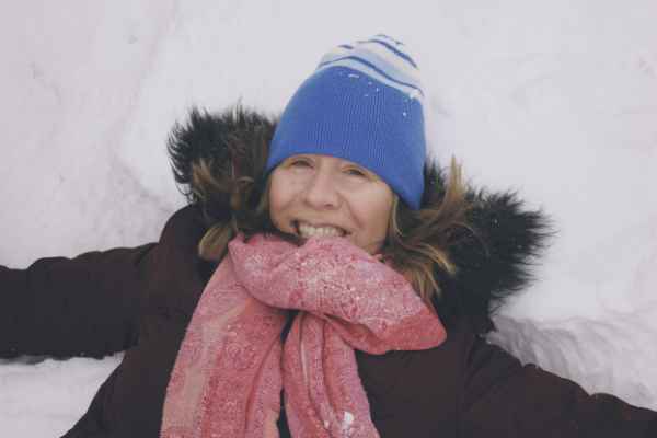 Lisa lays in the snow while wearing a winter jacket and cap in Yukon, Oklahoma